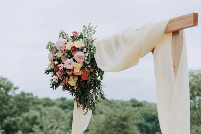 A wedding altar with a big bouquet of pink flowers on the right side of the poles